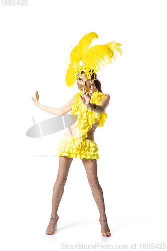 Image of Beautiful young woman in carnival, stylish masquerade costume with feathers dancing on white studio background. Concept of holidays celebration, festive time, dance, party, having fun