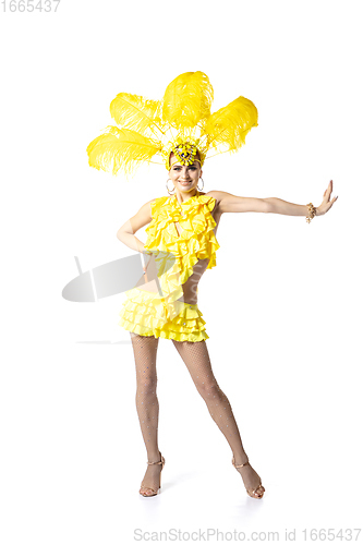 Image of Beautiful young woman in carnival, stylish masquerade costume with feathers dancing on white studio background. Concept of holidays celebration, festive time, dance, party, having fun