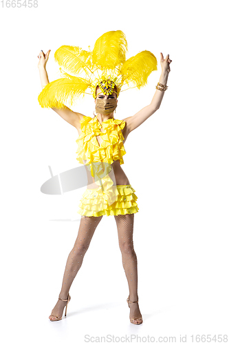Image of Beautiful young woman in carnival, stylish masquerade costume with feathers dancing on white studio background. Concept of holidays celebration, festive time, dance, party, having fun