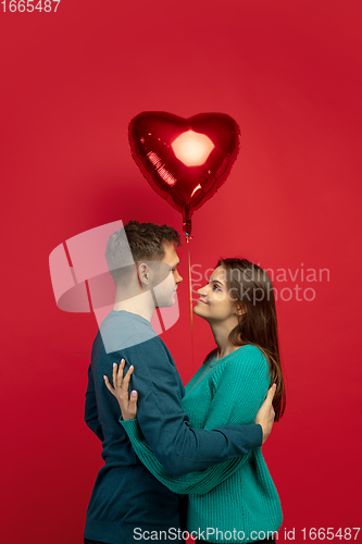 Image of Beautiful couple in love on red studio background. Valentine\'s Day, love and emotions concept