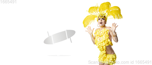 Image of Beautiful young woman in carnival, stylish masquerade costume with feathers dancing on white studio background.