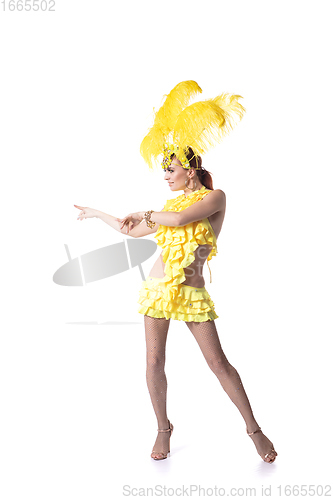 Image of Beautiful young woman in carnival, stylish masquerade costume with feathers dancing on white studio background.