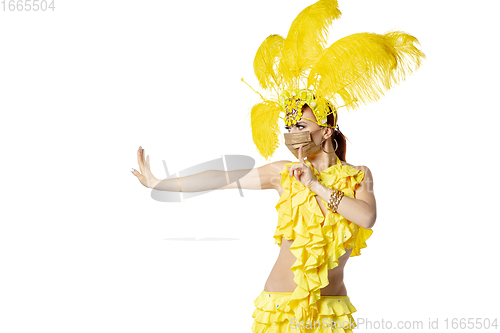 Image of Beautiful young woman in carnival, stylish masquerade costume with feathers dancing on white studio background.