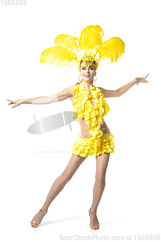 Image of Beautiful young woman in carnival, stylish masquerade costume with feathers dancing on white studio background.