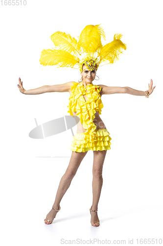 Image of Beautiful young woman in carnival, stylish masquerade costume with feathers dancing on white studio background.