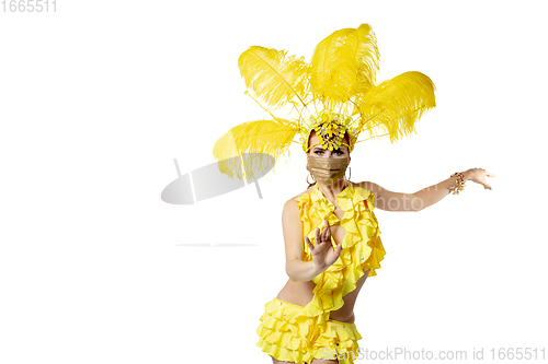 Image of Beautiful young woman in carnival, stylish masquerade costume with feathers dancing on white studio background.