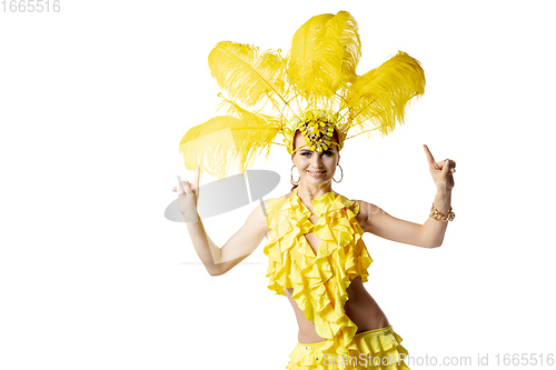 Image of Beautiful young woman in carnival, stylish masquerade costume with feathers dancing on white studio background.