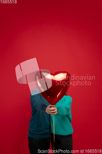 Image of Beautiful couple in love on red studio background. Valentine\'s Day, love and emotions concept