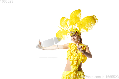 Image of Beautiful young woman in carnival, stylish masquerade costume with feathers dancing on white studio background.