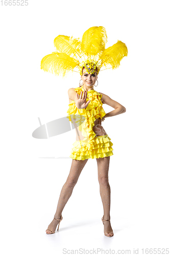 Image of Beautiful young woman in carnival, stylish masquerade costume with feathers dancing on white studio background.