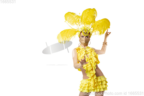 Image of Beautiful young woman in carnival, stylish masquerade costume with feathers dancing on white studio background.