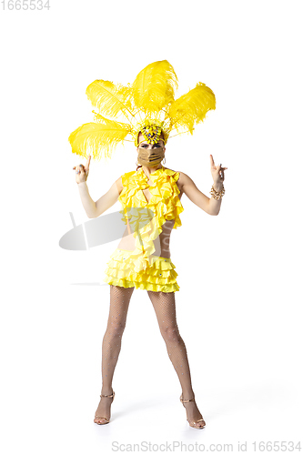 Image of Beautiful young woman in carnival, stylish masquerade costume with feathers dancing on white studio background.