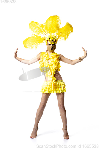 Image of Beautiful young woman in carnival, stylish masquerade costume with feathers dancing on white studio background.