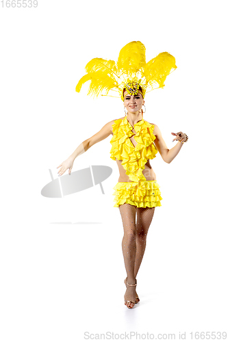 Image of Beautiful young woman in carnival, stylish masquerade costume with feathers dancing on white studio background.