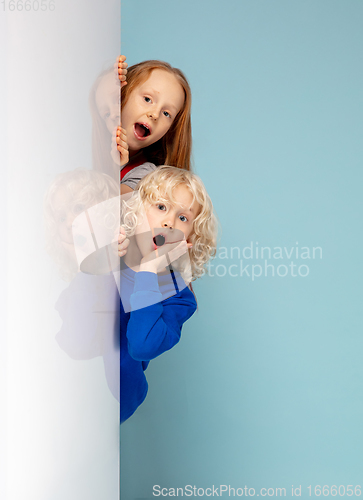 Image of Happy children isolated on blue studio background. Look happy, cheerful, sincere. Copyspace. Childhood, education, emotions concept
