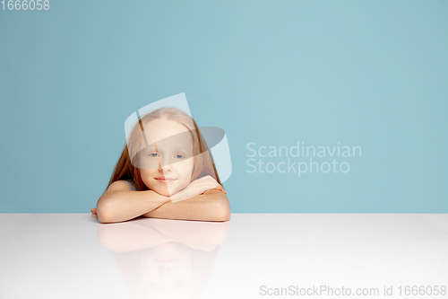 Image of Happy redhair girl isolated on blue studio background. Looks happy, cheerful, sincere. Copyspace. Childhood, education, emotions concept