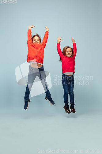 Image of Happy children isolated on blue studio background. Look happy, cheerful, sincere. Copyspace. Childhood, education, emotions concept