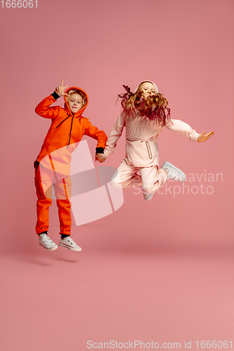 Image of Happy children isolated on coral pink studio background. Look happy, cheerful, sincere. Copyspace. Childhood, education, emotions concept