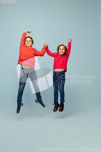 Image of Happy children isolated on blue studio background. Look happy, cheerful, sincere. Copyspace. Childhood, education, emotions concept