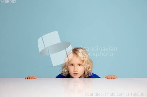 Image of Happy curly boy isolated on blue studio background. Looks happy, cheerful, sincere. Copyspace. Childhood, education, emotions concept