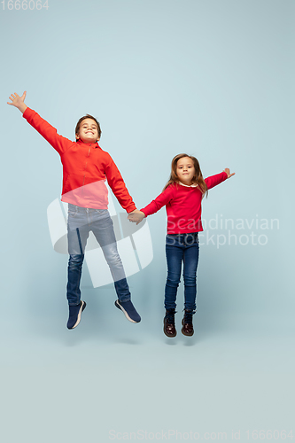 Image of Happy children isolated on blue studio background. Look happy, cheerful, sincere. Copyspace. Childhood, education, emotions concept
