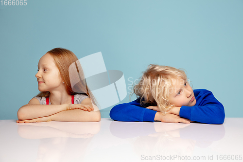 Image of Happy children isolated on blue studio background. Look happy, cheerful, sincere. Copyspace. Childhood, education, emotions concept