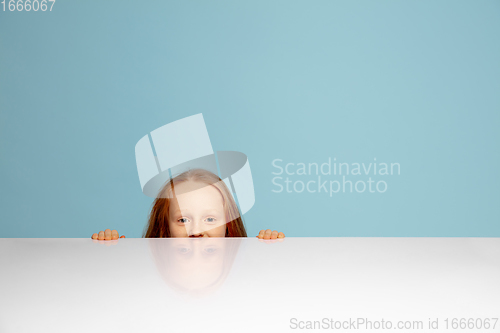 Image of Happy redhair girl isolated on blue studio background. Looks happy, cheerful, sincere. Copyspace. Childhood, education, emotions concept