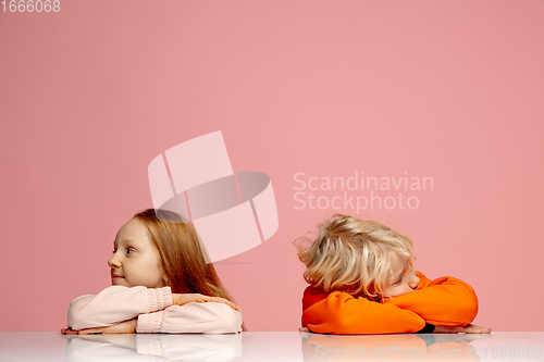 Image of Happy children isolated on coral pink studio background. Look happy, cheerful, sincere. Copyspace. Childhood, education, emotions concept