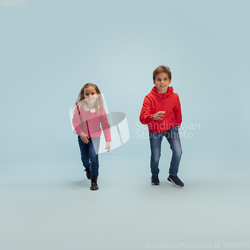 Image of Happy children isolated on blue studio background. Look happy, cheerful, sincere. Copyspace. Childhood, education, emotions concept