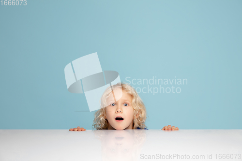 Image of Happy curly boy isolated on blue studio background. Looks happy, cheerful, sincere. Copyspace. Childhood, education, emotions concept