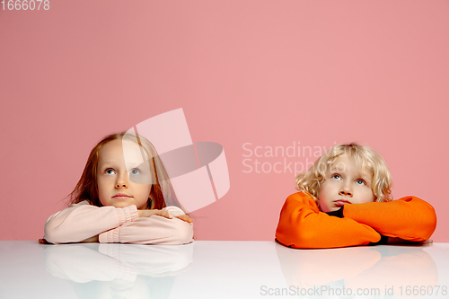 Image of Happy children isolated on coral pink studio background. Look happy, cheerful, sincere. Copyspace. Childhood, education, emotions concept