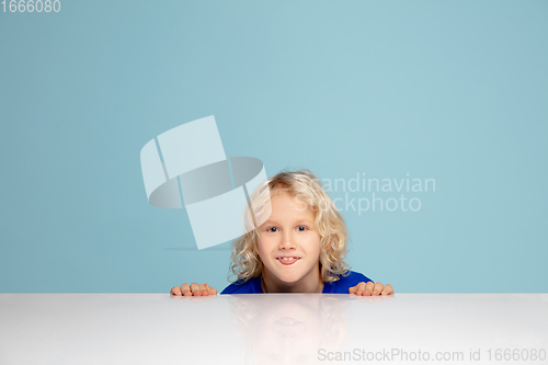 Image of Happy curly boy isolated on blue studio background. Looks happy, cheerful, sincere. Copyspace. Childhood, education, emotions concept