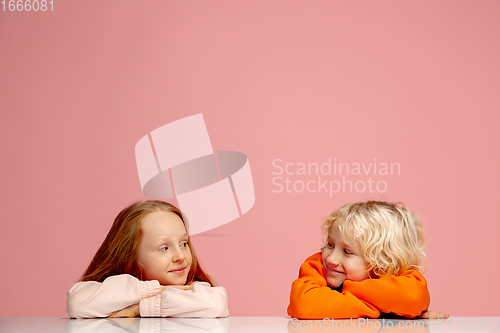 Image of Happy children isolated on coral pink studio background. Look happy, cheerful, sincere. Copyspace. Childhood, education, emotions concept