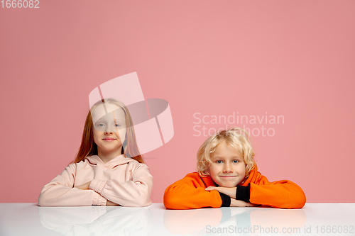 Image of Happy children isolated on coral pink studio background. Look happy, cheerful, sincere. Copyspace. Childhood, education, emotions concept