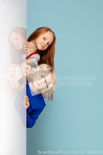 Image of Happy children isolated on blue studio background. Look happy, cheerful, sincere. Copyspace. Childhood, education, emotions concept