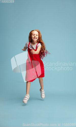 Image of Happy redhair girl isolated on blue studio background. Looks happy, cheerful, sincere. Copyspace. Childhood, education, emotions concept