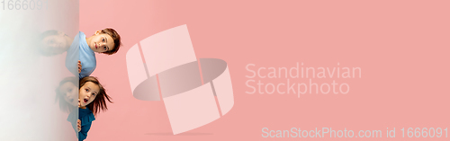Image of Happy children isolated on coral pink studio background. Look happy, cheerful, sincere. Copyspace. Childhood, education, emotions concept