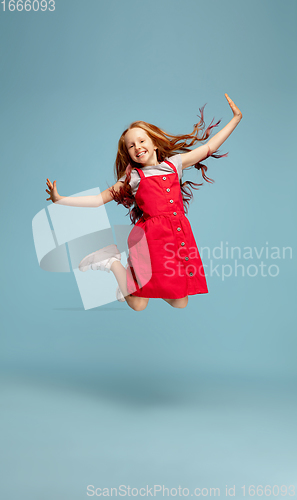 Image of Happy redhair girl isolated on blue studio background. Looks happy, cheerful, sincere. Copyspace. Childhood, education, emotions concept