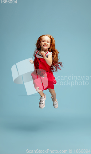 Image of Happy redhair girl isolated on blue studio background. Looks happy, cheerful, sincere. Copyspace. Childhood, education, emotions concept