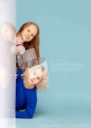 Image of Happy children isolated on blue studio background. Look happy, cheerful, sincere. Copyspace. Childhood, education, emotions concept