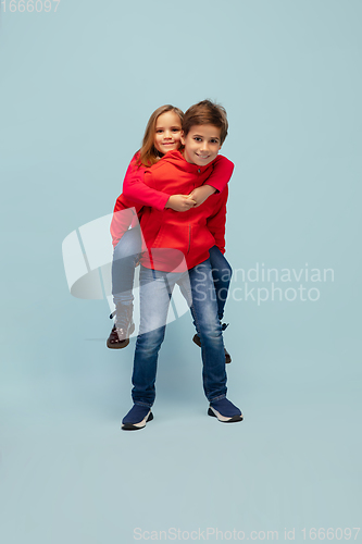 Image of Happy children isolated on blue studio background. Look happy, cheerful, sincere. Copyspace. Childhood, education, emotions concept