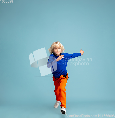 Image of Happy curly boy isolated on blue studio background. Looks happy, cheerful, sincere. Copyspace. Childhood, education, emotions concept