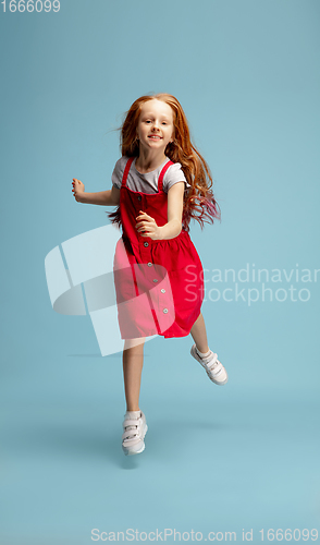 Image of Happy redhair girl isolated on blue studio background. Looks happy, cheerful, sincere. Copyspace. Childhood, education, emotions concept