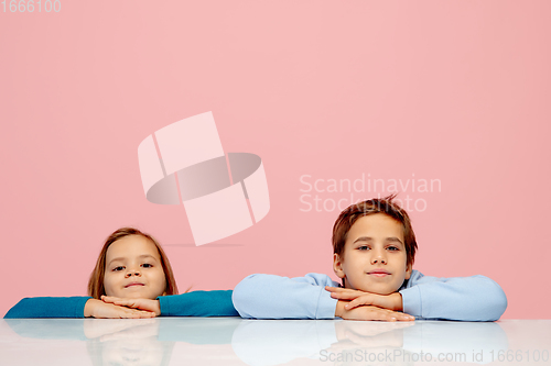 Image of Happy children isolated on coral pink studio background. Look happy, cheerful, sincere. Copyspace. Childhood, education, emotions concept