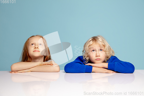 Image of Happy children isolated on blue studio background. Look happy, cheerful, sincere. Copyspace. Childhood, education, emotions concept