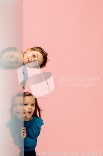 Image of Happy children isolated on coral pink studio background. Look happy, cheerful, sincere. Copyspace. Childhood, education, emotions concept