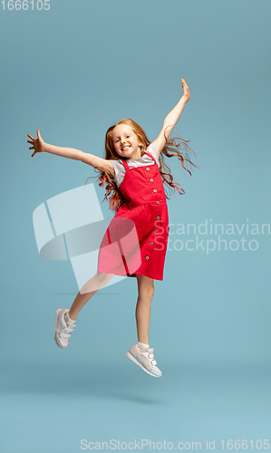 Image of Happy redhair girl isolated on blue studio background. Looks happy, cheerful, sincere. Copyspace. Childhood, education, emotions concept