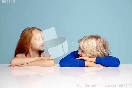 Image of Happy children isolated on blue studio background. Look happy, cheerful, sincere. Copyspace. Childhood, education, emotions concept