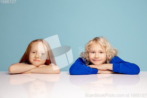 Image of Happy children isolated on blue studio background. Look happy, cheerful, sincere. Copyspace. Childhood, education, emotions concept