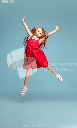 Image of Happy redhair girl isolated on blue studio background. Looks happy, cheerful, sincere. Copyspace. Childhood, education, emotions concept